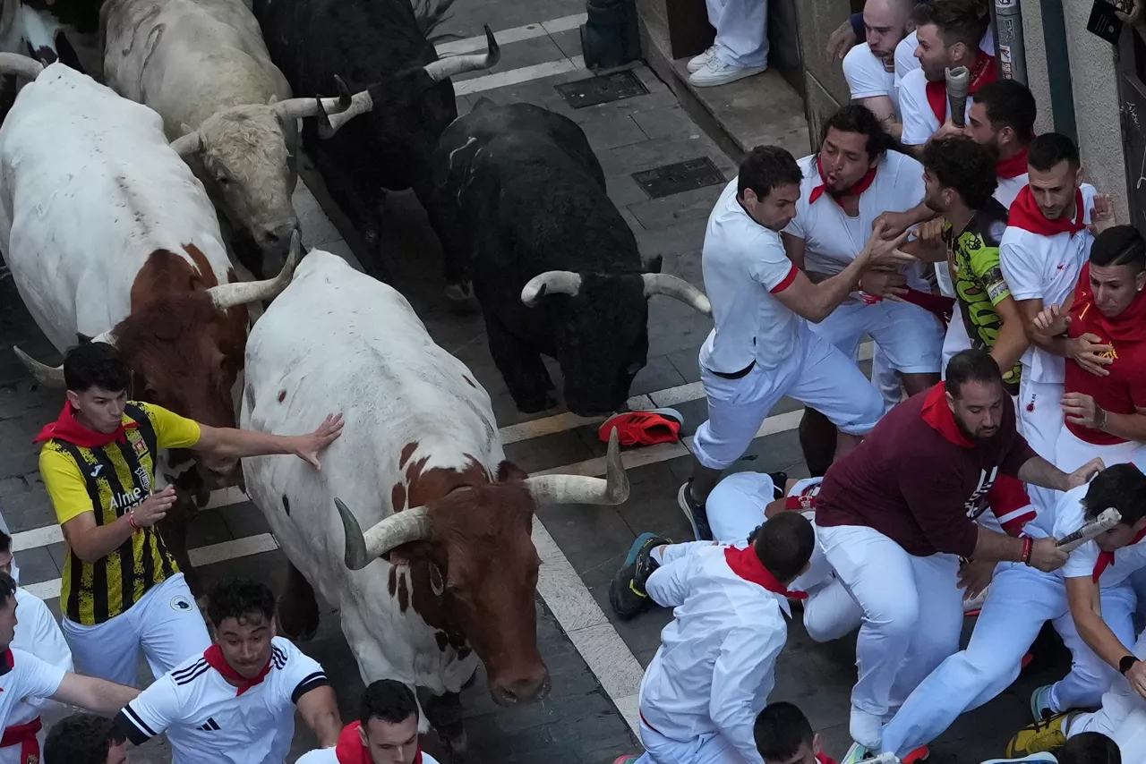 PAMPLONA, 07/07/2026.- Varios  mozos perseguidos por cabestros y toros de la ganadería gaditana de Fuente Ymbro en el tramo de la Estafeta, durante el primer encierro de los Sanferimes 2026, este martes en Pamplona. EFE/Ainhoa Tejerina
