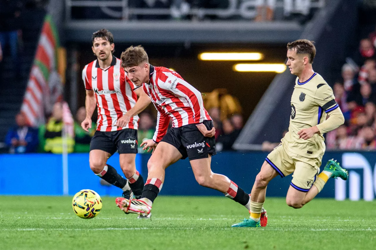 BILBAO, 07/03/2026.- El centrocampista del Athletic Club de Bilbao Mikel Jauregizar (c) juega el balón ante el centrocampista del Barcelona Marc Casadó (d), durante el partido de LaLiga en Primera División que disputan este sábado en el estadio de San Mamés, en Bilbao. EFE/Javier Zorrilla
