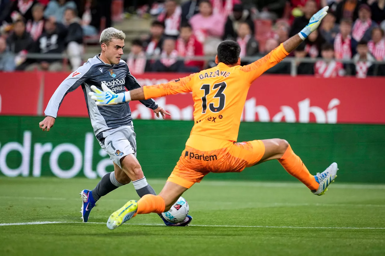 GERONA, 14/05/2026.- El centrocampista de la Real Sociedad Ander Barrenetxea (i) intenta superar a Paulo Gazzaniga, guardameta del Girona, durante el partido de la jornada 36 de LaLiga que Girona FC y Real Sociedad disputan este jueves en el estadio municipal de Montilivi. EFE/David Borrat.
