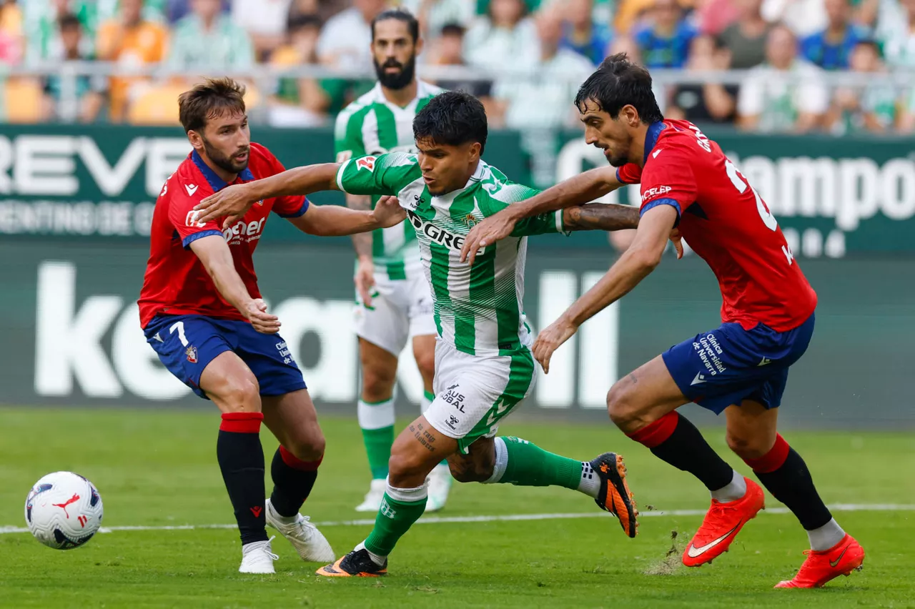 SEVILLA, 11/10/2026.- El delantero del Betis Cucho Hernández (c) trata de escapar entre Alejandro Catena (d) y Jon Mocayola, ambos de Osasuna, durante el partido de LaLiga de fútbol que Real Betis y CA Osasuna disputan este domingo en el estadio de La Cartuja, en Sevilla. EFE/Julio Muñoz
