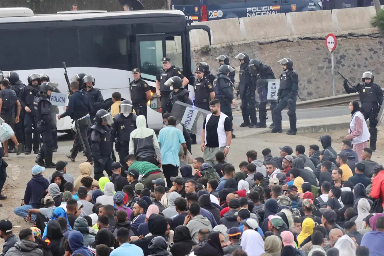 CEUTA, 04/10/2026.- La Policía Nacional ha puesto en marcha a primeras horas de la mañana de este domingo un dispositivo para comenzar a levantar el asentamiento de la playa del Trampolín, donde viven más de 3.000 migrantes.Los migrantes se trasladarán en autobuses hasta el CATE situado en la frontera del Tarajal, donde se les realizará el correspondiente triaje para su identificación. EFE/ Reduán
