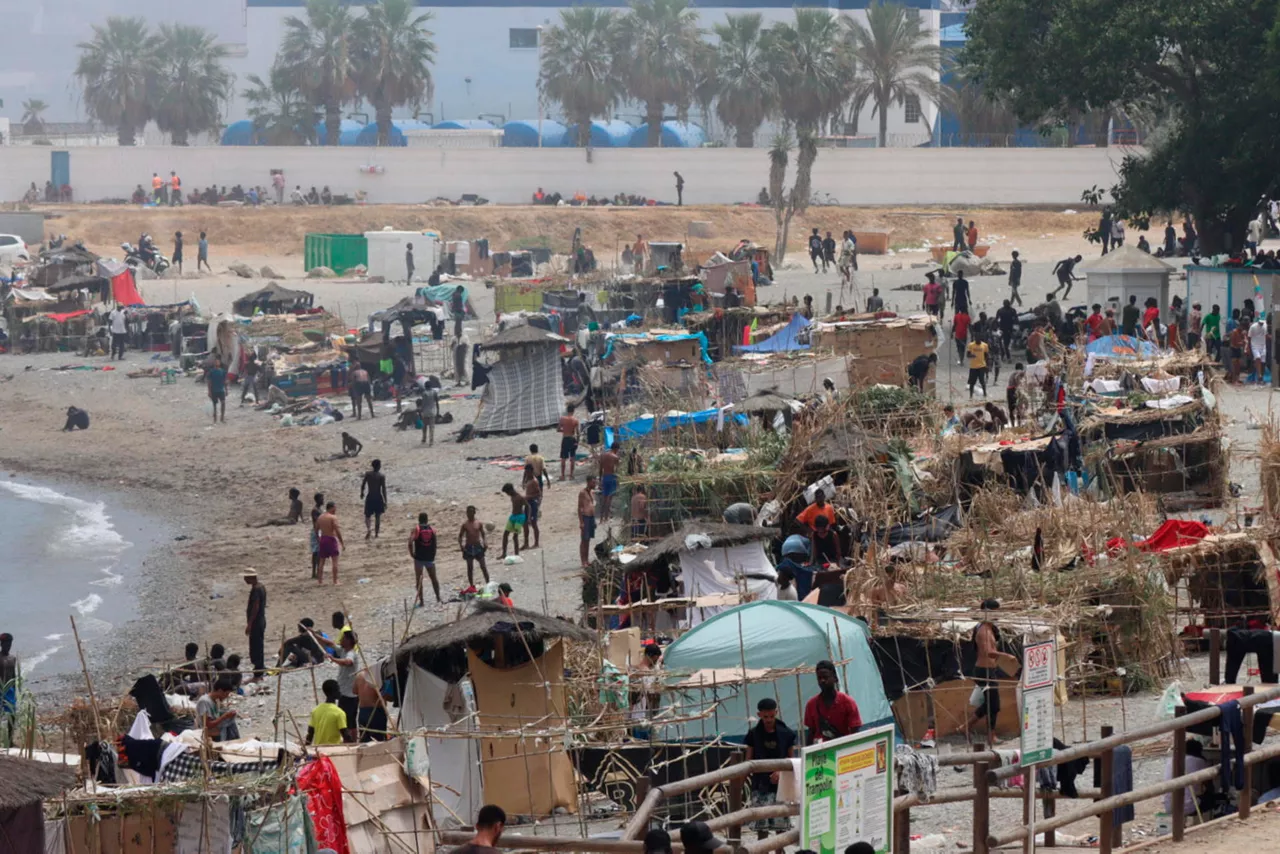 FOTODELDÍA - CEUTA, 14/08/2026.- Vista de la playa ‘El Trampolín’ de Ceuta donde se encuentran cientos de los migrantes que llegaron a la playa del Tarajal. La entrada masiva de migrantes desde Marruecos a Ceuta, el 30 de julio, ha provocado una tragedia sin precedentes en esta frontera, con más de 70.000 personas que cruzaron a pie o nado al enclave español; 141 muertos, según organizaciones humanitarias, y tensiones entre Madrid y Rabat. EFE/Reduan
