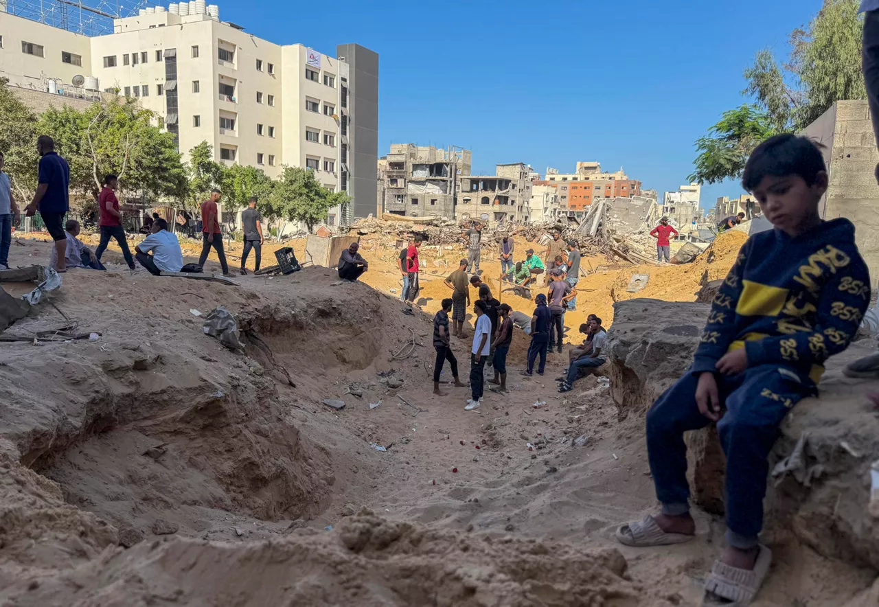 GAZA (GAZA Y CISJORDANIA), 21/09/2025.- En una fosa común improvisada detrás del Hospital Shifa, en la ciudad de Gaza, decenas de familias entierran a sus seres queridos este domingo, mientras la operación terrestre de Israel se expande, temerosos de que buscar un lugar de entierro digno les ponga en riesgo. Los cuerpos, envueltos en telas blancas, son depositados en un hoyo abierto en la arena. A su alrededor, edificios derrumbados y el zumbido constante de drones conforman el escenario de un duelo sin pausa. EFE/ Ahmad Awad

