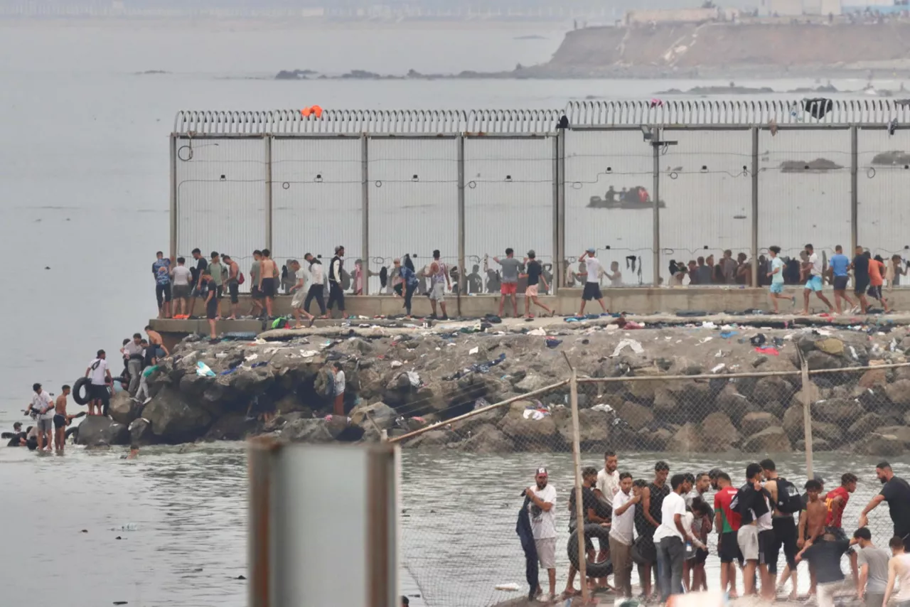 CEUTA, 31/07/2026.- Centenares de migrantes que en las últimas horas habían accedido de forma irregular a Ceuta, han comenzado a regresar a Marruecos por el mismo punto por el que entraron, el espigón fronterizo que separa la ciudad autónoma con el país vecino, según ha podido comprobar EFE. De forma paralela, continúan entrando en la ciudad pequeños grupos de personas por ese mismo lugar, cruzándose en su camino con lo que abandonan Ceuta en dirección a Marruecos. EFE/ Reduan Dris
