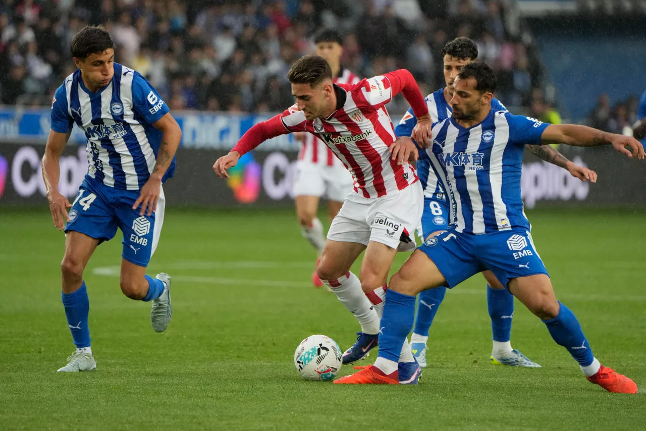 VITORIA, 02/05/2026.- El centrocampista del Athletic Robert Navarro (c) pelea un balón con Toni Martínez (d) y Nahuel Tenaglia, ambos del Alavés, durante el partido de LaLiga de fútbol que Deportivo Alavés y Athletic Club disputan este sábado en el estadio de Mendizorrotza, en Vitoria. EFE/Adrián Ruiz Hierro
