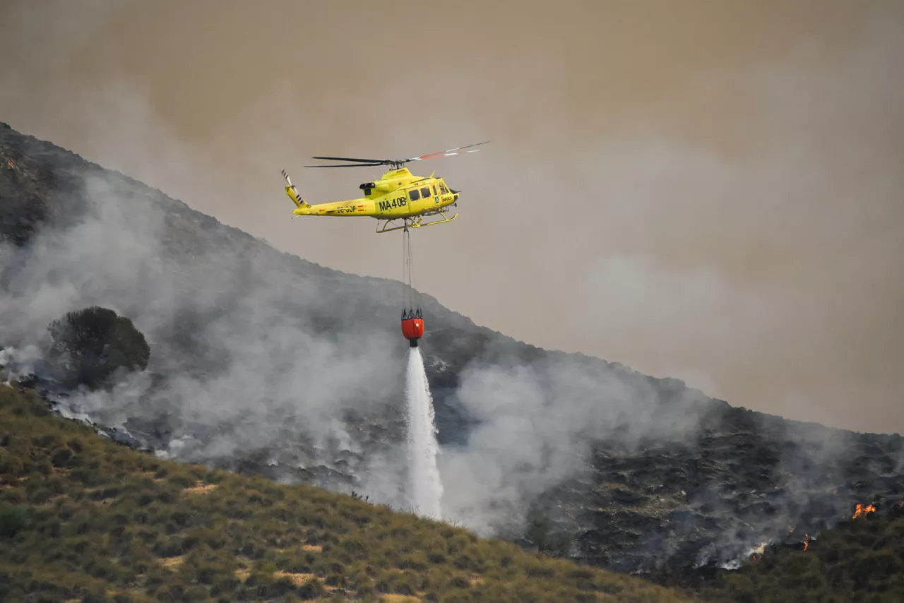 FOTODELDIA ALMERÍA, 10/07/2026.-Un helicóptero del servicio de extinción de incendios arroja este viernes agua sobre uno de los focos del incendio forestal declarado en Los Gallardos, Almería, que se ha convertido en una tragedia sin precedentes en la zona y uno de los más graves de España, con un balance provisional de 12 personas fallecidas, ocho heridas y 19 desaparecidas. EFE/ Carlos Barba
