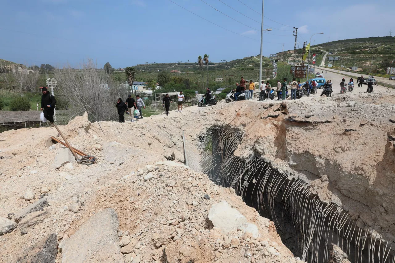 Beirut (Lebanon), 17/04/2026.- Displaced people walk with their belongings near a damaged part of the Qasmiyeh Bridge as they return to their homes near Tyre, southern Lebanon, 17 April 2026. Israel and Lebanon have agreed to a 10-day ceasefire, which went into effect at midnight on 16 April. (Líbano) EFE/EPA/WAEL HAMZEH
