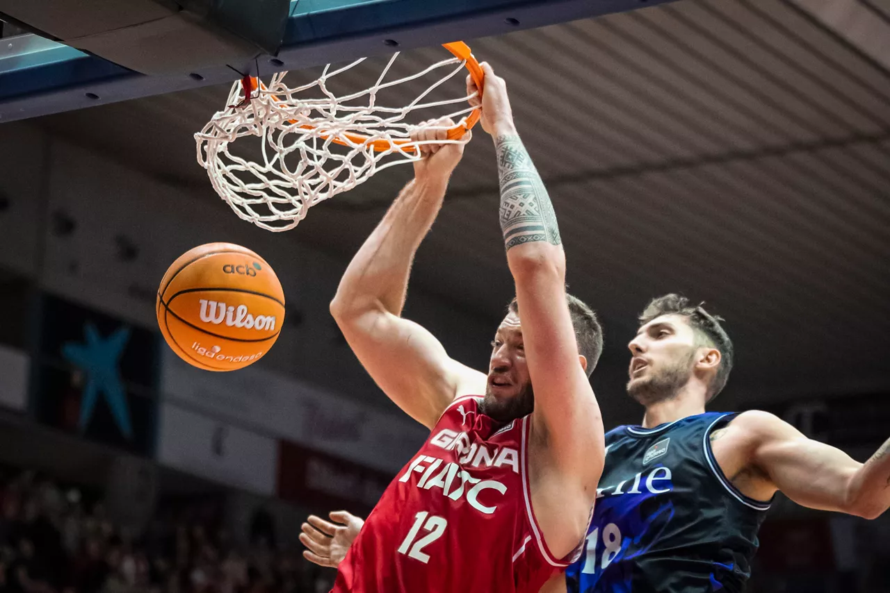 GERONA, 04/01/2026.- Martinas Geben (i), del Basquet Girona, machaca la canasta junto a Luke Petrasek, del Bilbao Basket, en el partido de la Liga Endesa entre el Basquet Girona y Surne Bilbao, este domingo en el pabellón de Fontajau. EFE/David Borrat.
