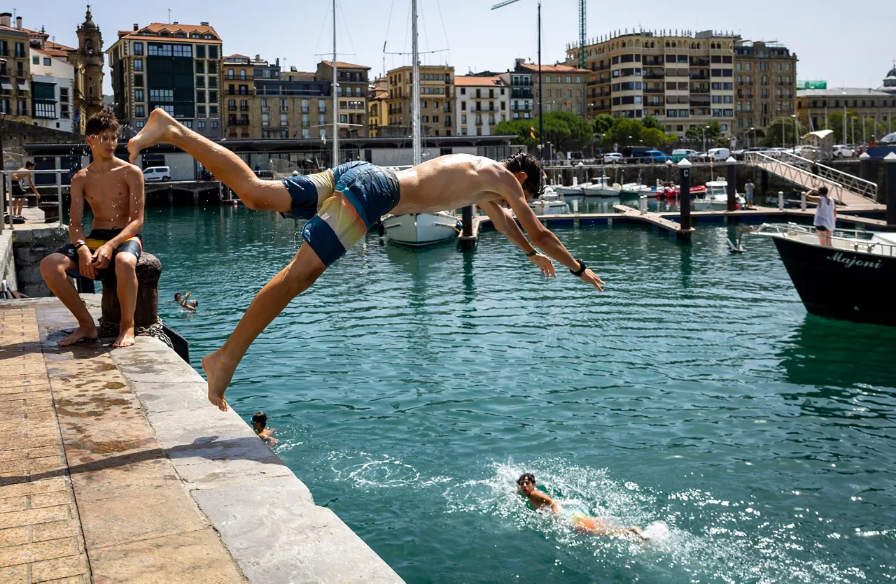 SAN SEBASTIÁN, 22/06/2026.- Un juven se lanza al agua este lunes en el puerto de San Sebastián. Los cielos en Euskadi se presentan hoy poco nubosos o despejados y con posibilidad de algún chubasco disperso tormentoso en el sur, en una nueva jornada de calor sofocante que volverá a dejar máximas de entre 35 y 40 grados en los tres territorios. EFE/ Javier Etxezarreta
