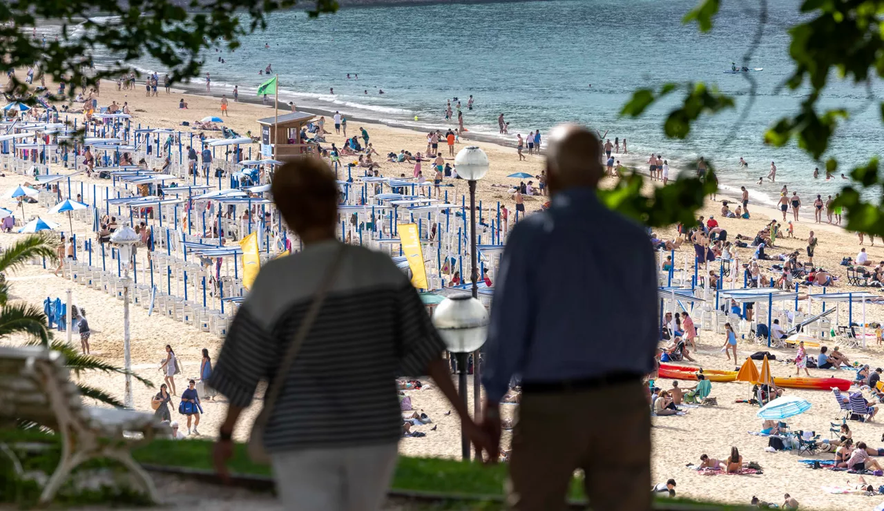 SAN SEBASTIÁN, 20/06/2026.- Una pareja pasea por la sombra este sábado junto la playa de Ondarreta de San Sebastián. Los cielos en Euskadi se presentan este domingo con escasa nubosidad para recibir la temporada estival con calor de pleno verano y temperaturas que superarán los 35 grados en los tres territorios, y los 40º en algunos puntos.EFE/Javier Etxezarreta
