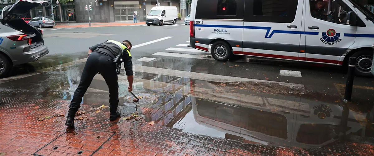 GRAFCAV286. BILBAO, 04/10/2026.-Un policía municipal de Bilbao, alivia un alcantarillado tras sufrir la pasada noche un total de 150 incidencias por la intensa lluvia en Bizkaia, con numerosas inundaciones y basas de agua en las carreteras.La alerta naranja da paso a un aviso amarillo que ha finalizado a las 06:00 este domingo.EFE/Luis Tejido
