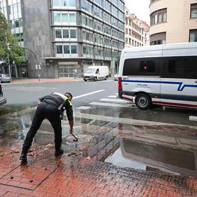 GRAFCAV286. BILBAO, 04/10/2026.-Un policía municipal de Bilbao, alivia un alcantarillado tras sufrir la pasada noche un total de 150 incidencias por la intensa lluvia en Bizkaia, con numerosas inundaciones y basas de agua en las carreteras.La alerta naranja da paso a un aviso amarillo que ha finalizado a las 06:00 este domingo.EFE/Luis Tejido
