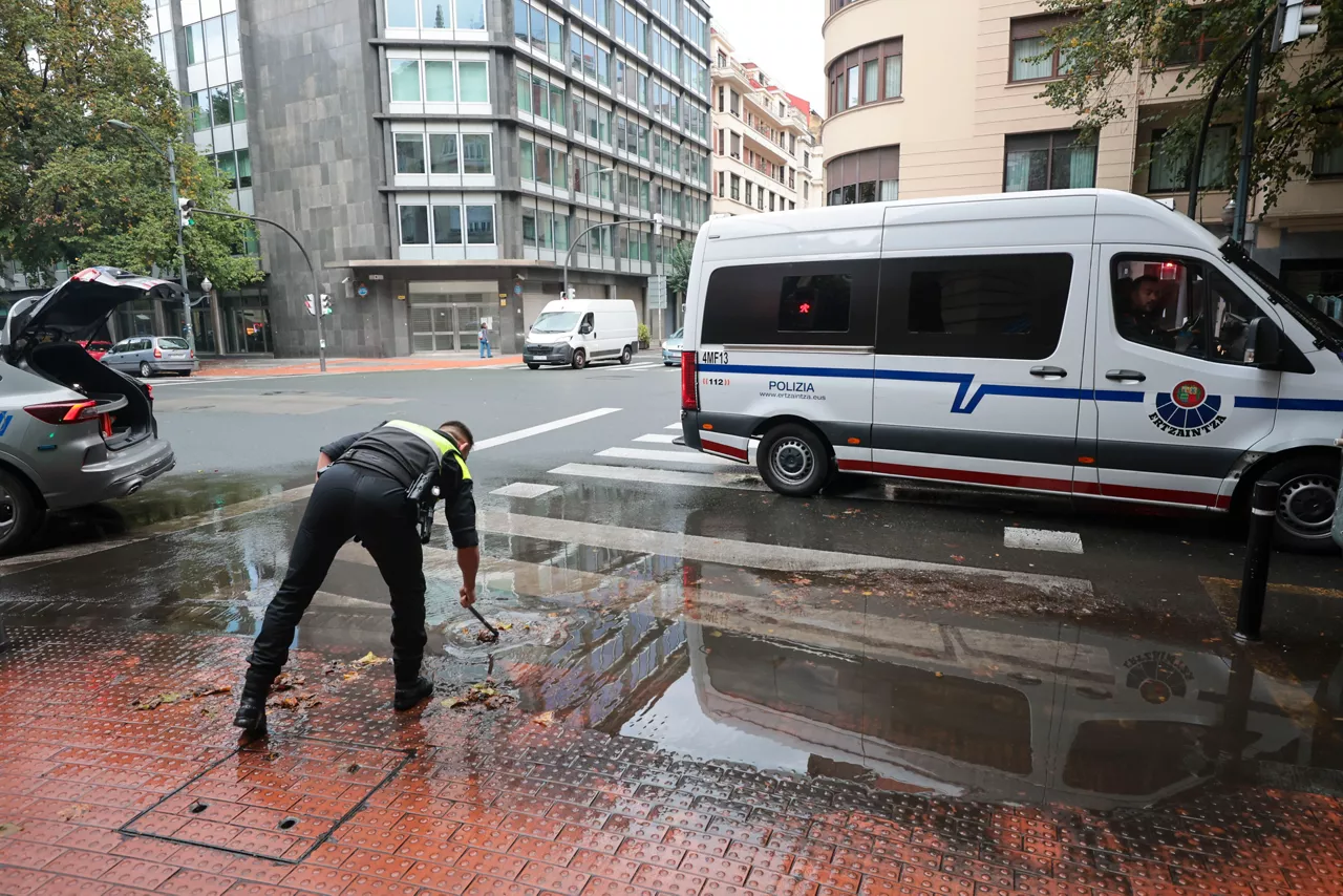 GRAFCAV286. BILBAO, 04/10/2026.-Un policía municipal de Bilbao, alivia un alcantarillado tras sufrir la pasada noche un total de 150 incidencias por la intensa lluvia en Bizkaia, con numerosas inundaciones y basas de agua en las carreteras.La alerta naranja da paso a un aviso amarillo que ha finalizado a las 06:00 este domingo.EFE/Luis Tejido
