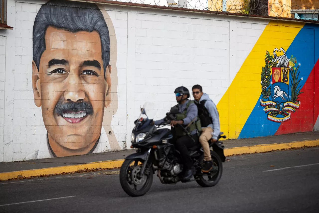 AME2070. CARACAS (VENEZUELA), 04/01/2026.- Personas transitan frente a un mural del presidente de Venezuela, Nicolás Maduro, este domingo en Caracas (Venezuela). Maduro pasa su primera noche recluido en la cárcel federal Metropolitan Detention Center de Brooklyn, en Nueva York, tras ser capturado hace menos de 24 horas por Estados Unidos en Caracas, donde su vicepresidenta, Delcy Rodríguez, recibió la orden del Tribunal Supremo venezolano de asumir como presidenta encargada del país. EFE/ Ronald Peña R
