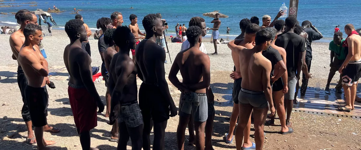 FOTODELDÍA CEUTA, 05/08/2026.- Los jóvenes inmigrantes que duermen en la calle hacen cola para ducharse en la playa del Trampolín, tras acceder a Ceuta el pasado jueves durante la entrada masiva por el espigón fronterizo protagonizada por más de 70.000 personas y que permanecen en la ciudad, entre ellos 528 menores. EFE/ Reduan
