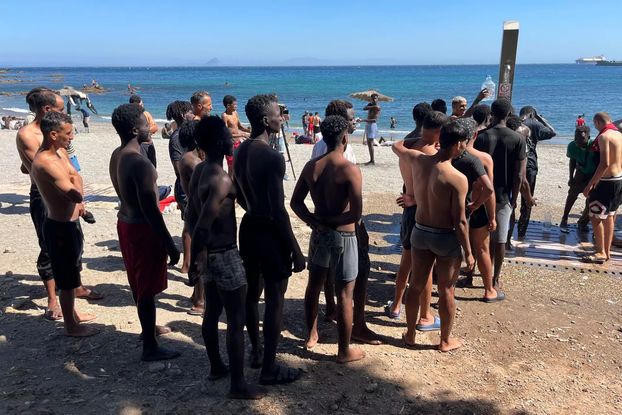 FOTODELDÍA CEUTA, 05/08/2026.- Los jóvenes inmigrantes que duermen en la calle hacen cola para ducharse en la playa del Trampolín, tras acceder a Ceuta el pasado jueves durante la entrada masiva por el espigón fronterizo protagonizada por más de 70.000 personas y que permanecen en la ciudad, entre ellos 528 menores. EFE/ Reduan

