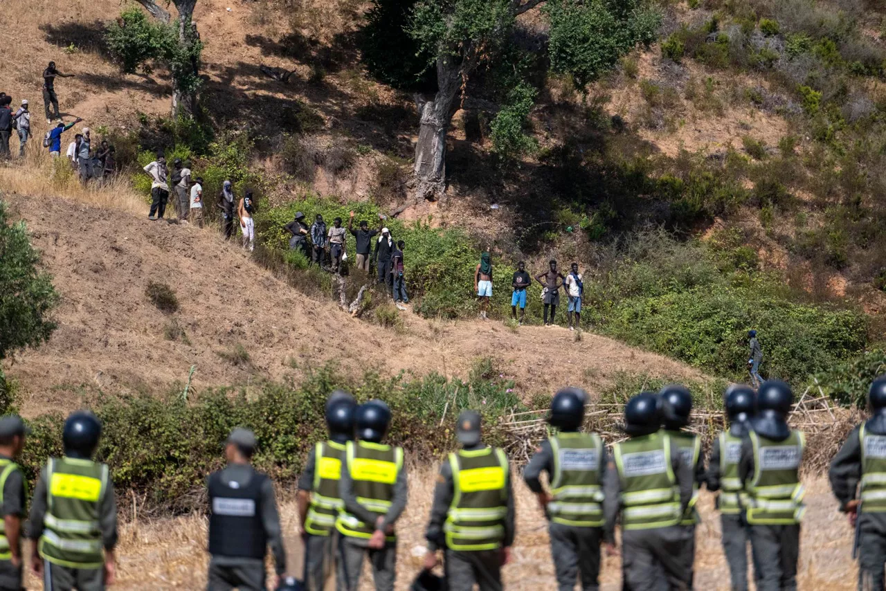 Castillejos (Morocco), 15/08/2026.- Moroccan security forces monitor as they thwart attempts by hundreds of sub-Saharan African and Sudanese migrants who have gathered to enter the Spanish city of Ceuta in Fnideq (Castillejos), Morocco, 15 August 2026. Moroccan security sources report that the incident took place in a mountainous area on the outskirts of Castillejos, southwest of Ceuta. (Marruecos, España) EFE/EPA/JALAL MORCHIDI
