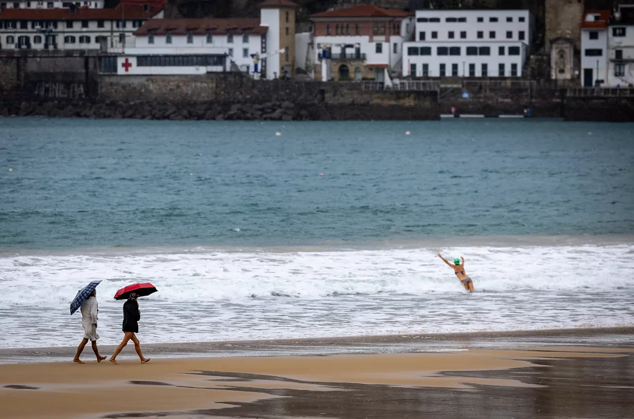 FOTODELDÍA SAN SEBASTIÁN, 24/11/2025.- Dos mujeres pasean bajo sus paraguas este lunes por la playa de La Concha de San Sebastián. El tiempo previsto para hoy en Euskadi es de cielo muy nuboso o cubierto, precipitaciones débiles que a partir del mediodía aumentarán en intensidad y serán muy abundantes en la vertiente cantábrica, donde habrá también posibilidad de que caigan en forma de tormentas, y cota de nieve que podría bajar a 1.200 metros por la noche.EFE/Javier Etxezarreta
