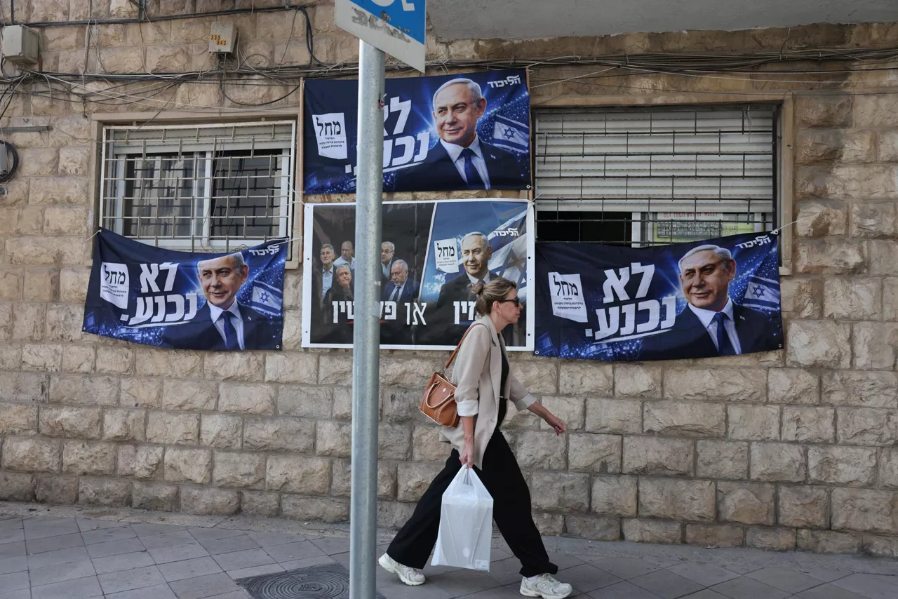 Jerusalem (-), 21/10/2026.- A woman passes by an election billboard of Israeli Prime Minister Benjamin Netanyahu with Hebrew slogan reading 'will not surrender' in Jerusalem, 21 October 2026. Israel will hold legislative elections on 27 October 2026. (Elecciones, Jerusalén) EFE/EPA/ABIR SULTAN
