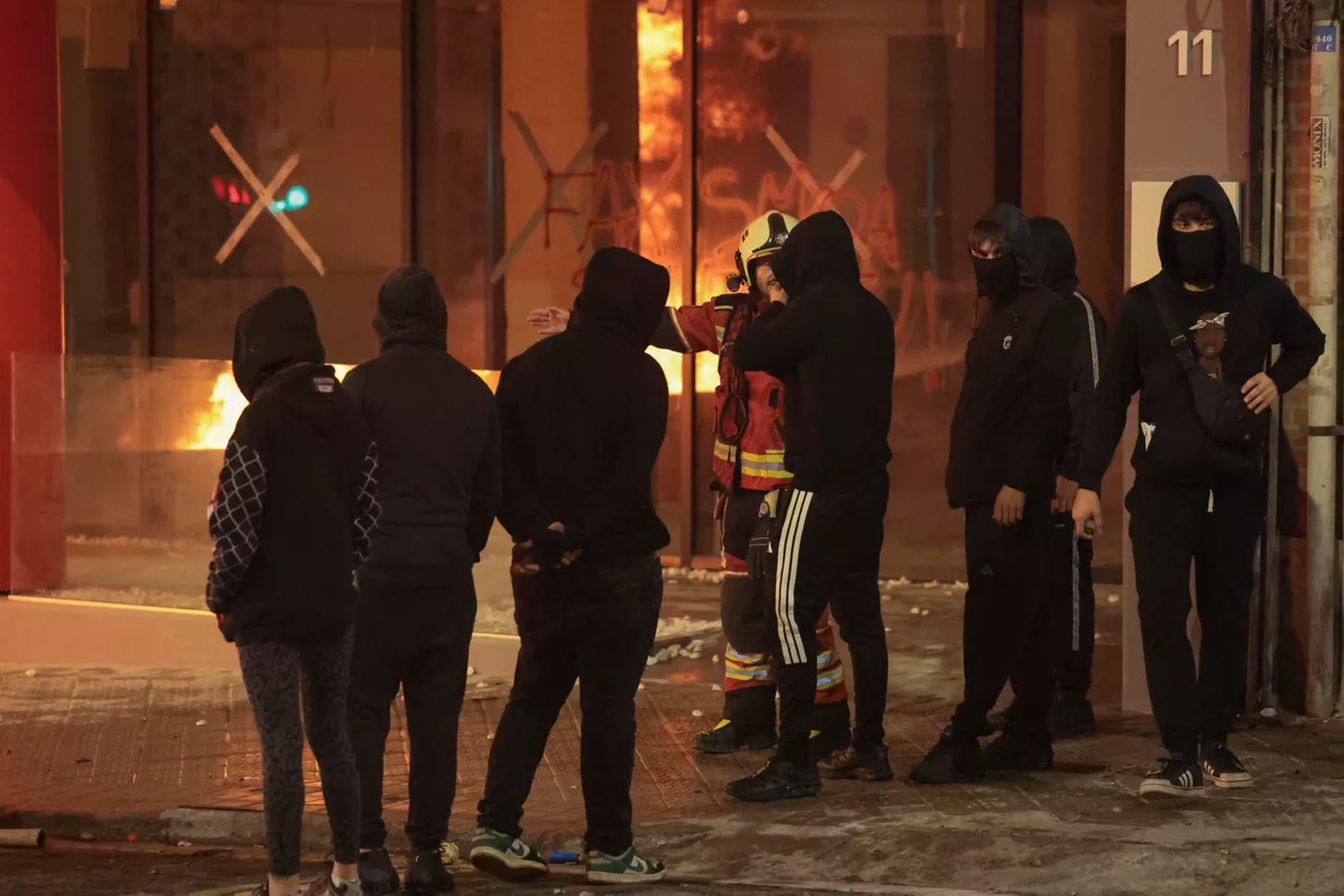 BILBAO, 26/10/2026.- Un bombero habla con un grupo de asistentes a la manifestación de estudiantes y de colectivos 'antifascistas' este lunes por el centro de Bilbao "contra el fascismo" y en protesta por el acto anunciado por el agitador y activista político Vito Quiles para esta tarde en la ciudad. EFE/Luis Tejido
