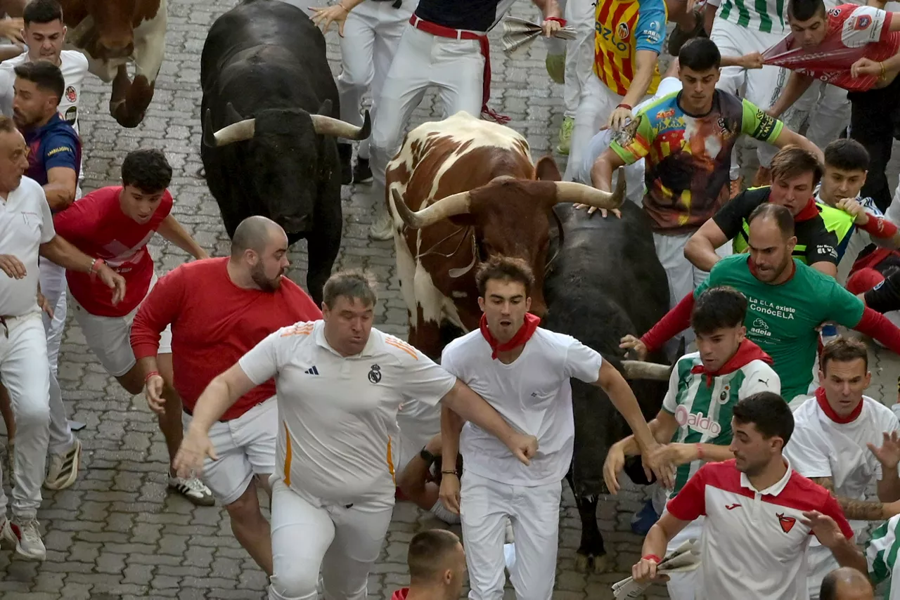 PAMPLONA, 09/07/2026.- Los toros de la ganadería madrileña de Victoriano del Río rodeados por los mozos durante el tercer encierro de los Sanfermines 2026, este jueves en Pamplona. EFE/José Luis Larrión

