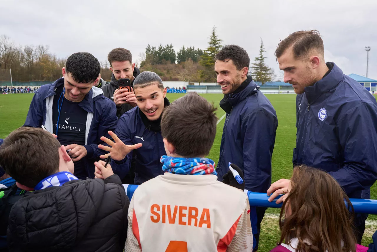 VITORIA, 30/09/2025 .- Los jugadores del Deportivo Alaves, Carles Aleña (i), Joussef Enriquez (2i), Ander Guevara (2d) y Toni Martínez bromean con un niño tras el entrenamiento de puertas abiertas que han celebrado hoy martes. EFE/Adrián Ruiz-Hierro
