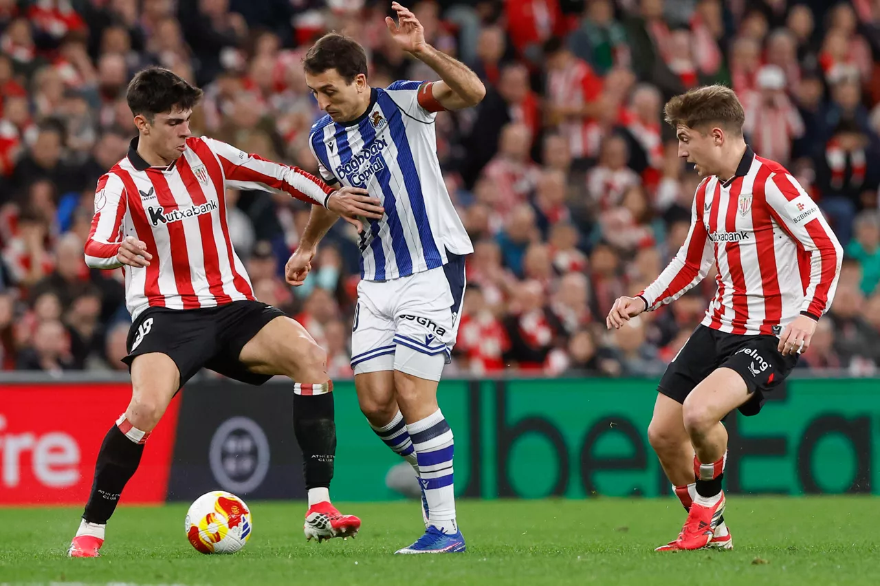 BILBAO, 11/02/2026.- El delantero de la Real Mikel Oyarzabal (c) pelea un balón con Alejandro Rego (i) y Mikel Jauregizar, ambos del Athletic, durante el partido de ida de la semifinales de la Copa del Rey que Athletic Club y Real Sociedad disputan este miércoles en el estadio de San Mamés, en Bilbao. EFE/Miguel Toña

