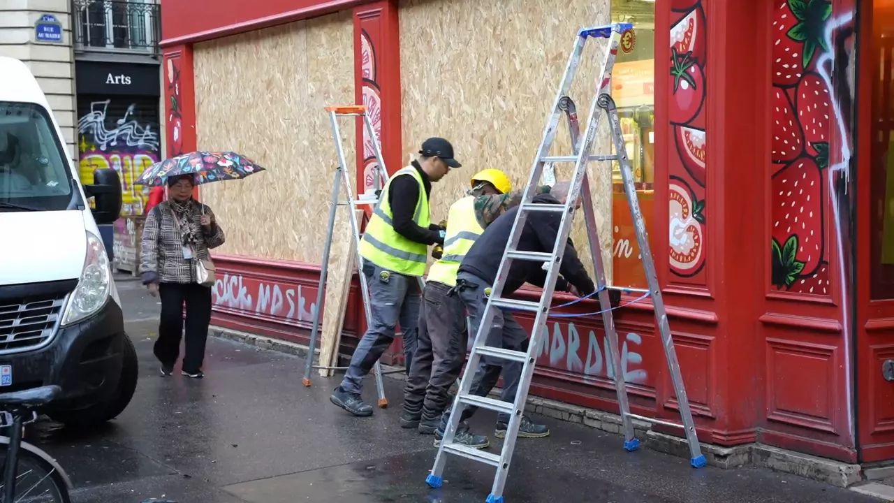 SCREENSHOT - 23 October 2026, France, Paris: Workers board up the entrances and windows of shops with wooden planks. Photo: Alexander Franz/dpa