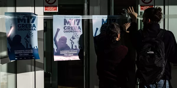 Personas colocando carteles de la huelga general en Donostia. Foto: EFE