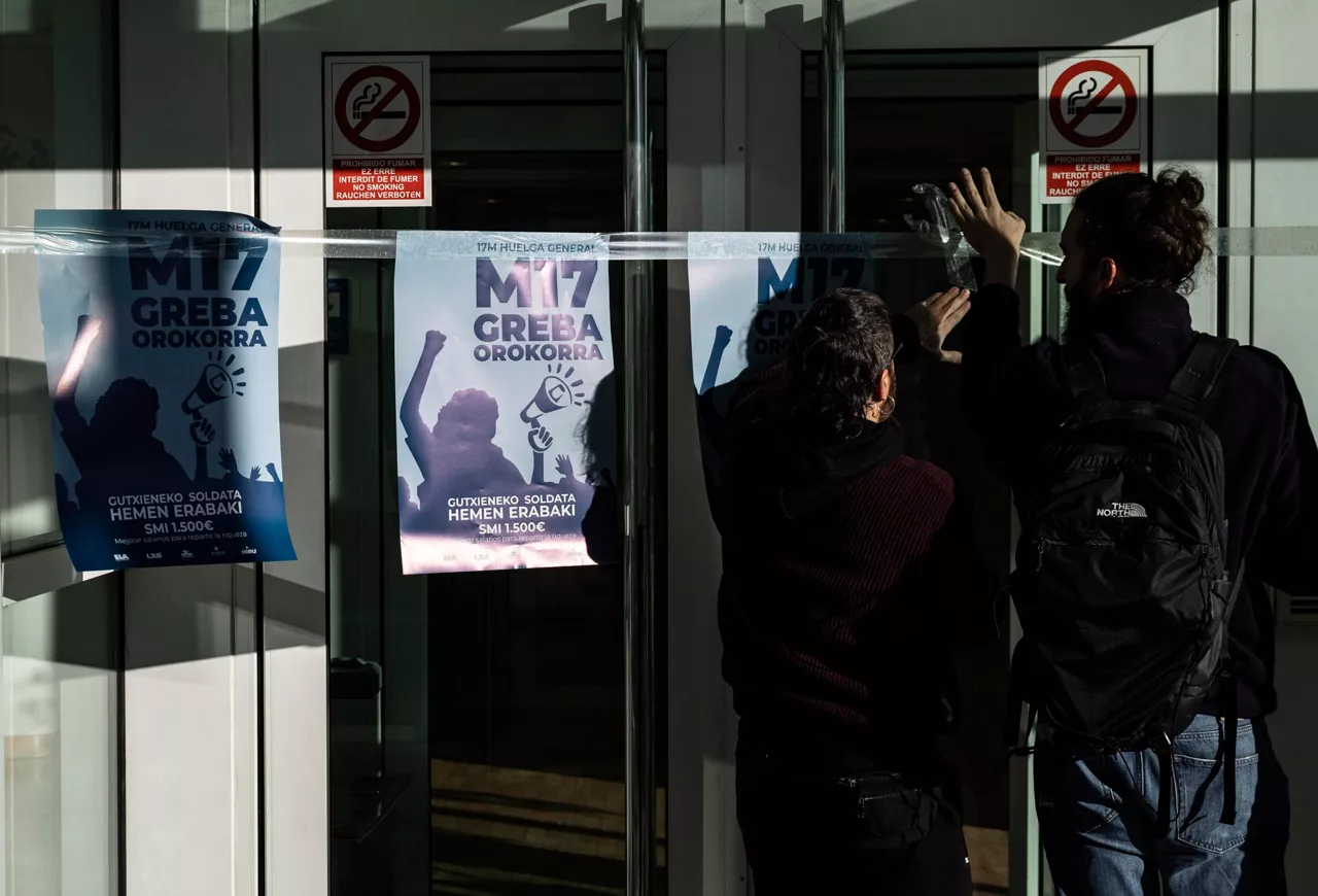 Personas colocando carteles de la huelga general en Donostia. Foto: EFE