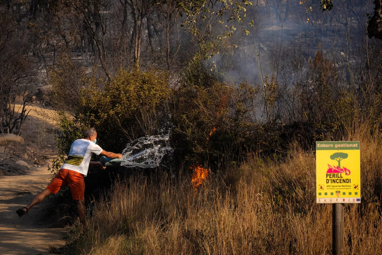 CALONGE (GIRONA), 04/07/2026.- Un vecino intenta apagar una zona en llamas en la localidad de Calonge este sábado tras el incendio forestal que comenzó ayer en La Bisbal de l'Empordà (Girona). EFE/David Borrat
