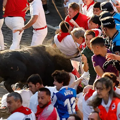 PAMPLONA, 14/07/2026.- Un toro de la ganadería extremeña de Jandilla embiste a varios mozos a su paso por la calle Mercaderes, durante el último encierro de los Sanfermines 2026, este martes en Pamplona. EFE/Villar López
