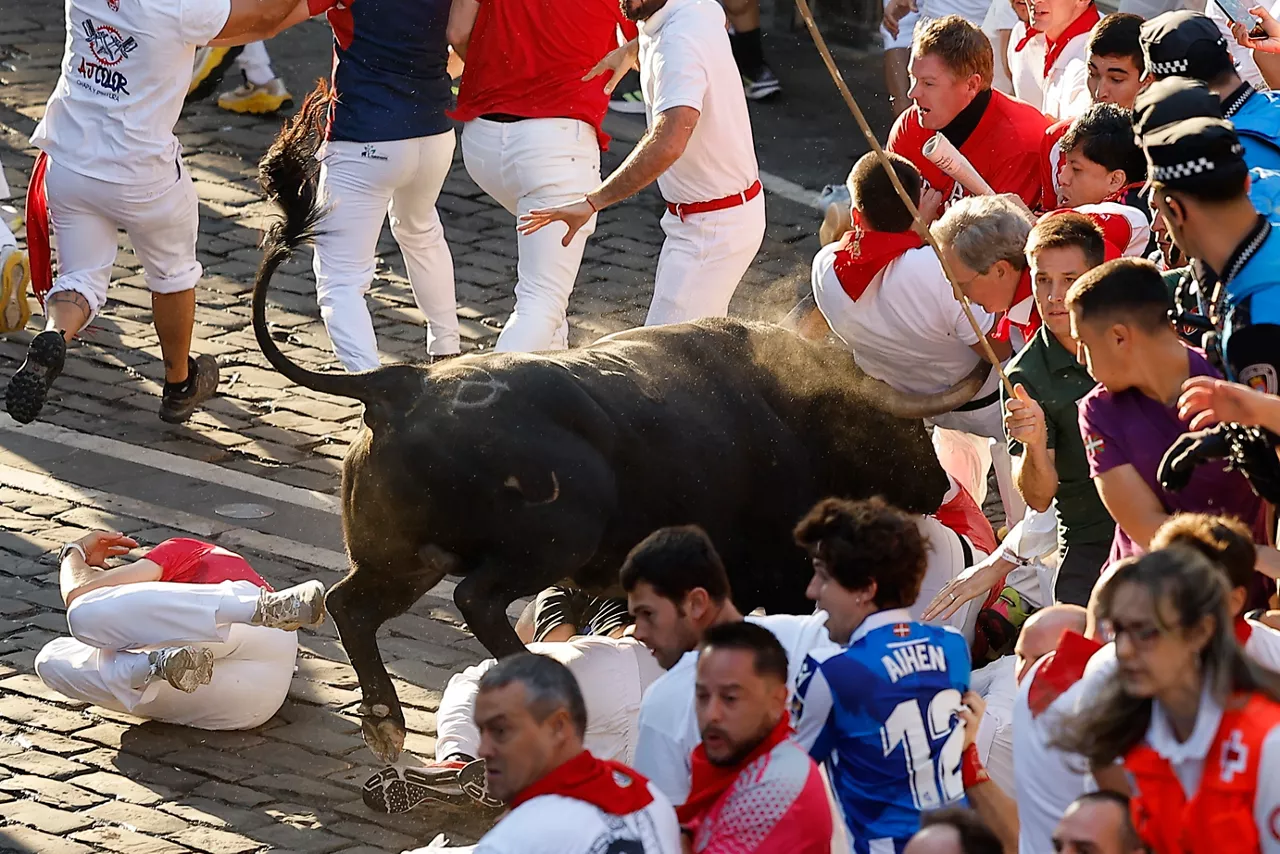 PAMPLONA, 14/07/2026.- Un toro de la ganadería extremeña de Jandilla embiste a varios mozos a su paso por la calle Mercaderes, durante el último encierro de los Sanfermines 2026, este martes en Pamplona. EFE/Villar López
