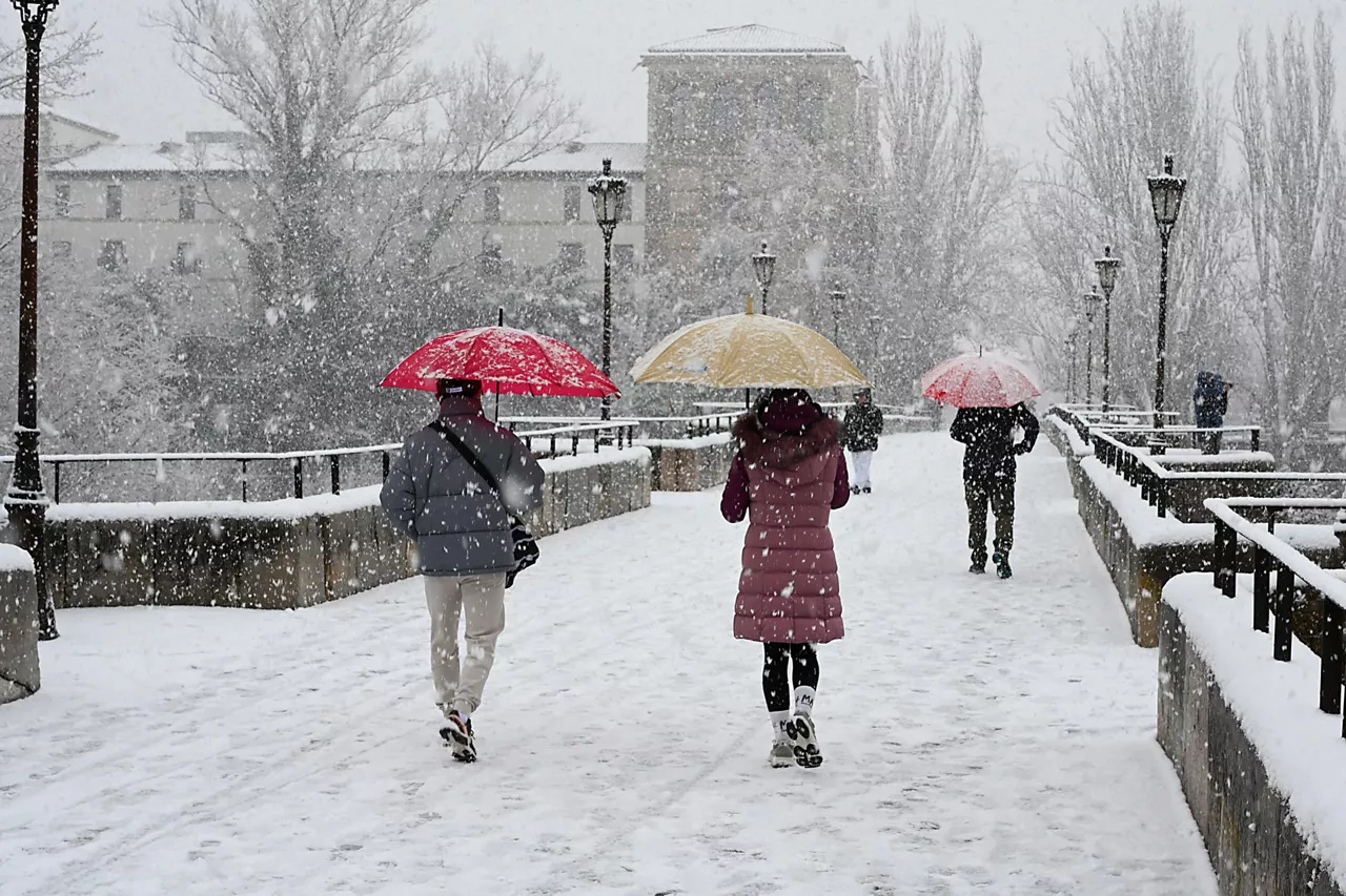 LEÓN, 28/01/2026.- Varias personas caminan entre la nieve caída este miércoles en León. El temporal está dejando o intensas nevadas en la provincia de León con incidencias en el transporte por carretera y el incremento de caudal en las vías fluviales tras encadenar sucesivas borrascas en los últimos días, lo que también ha impedido 732 alumnos no hayan podido asistir a clase en varias localidades de la Montaña Leonesa. EFE/J.Casares
