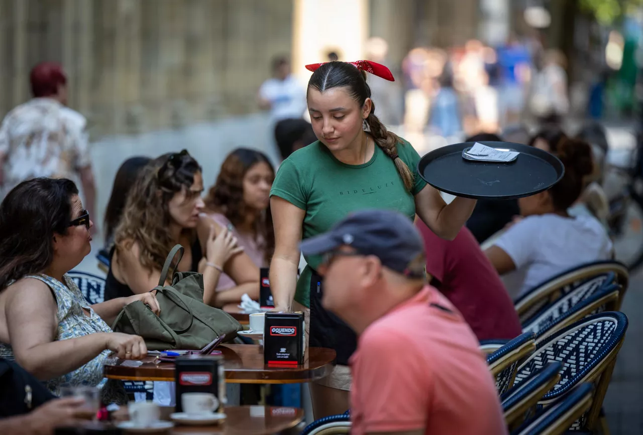 SAN SEBASTIÁN, 28/07/2026.- Una mujer atiende una terraza en San Sebastián este martes, en el que se han publicado la Encuesta de Población Activa. El mercado laboral creó en el segundo trimestre de 2026 en el País Vasco 7.800 empleos hasta un total de 1.007.600, mientras la cifra de desempleados se redujo en 12.400 y la tasa de paro bajó 1,12 puntos respecto a los últimos tres meses del año anterior hasta el 7,11 %. EFE/Javier Etxezarreta
