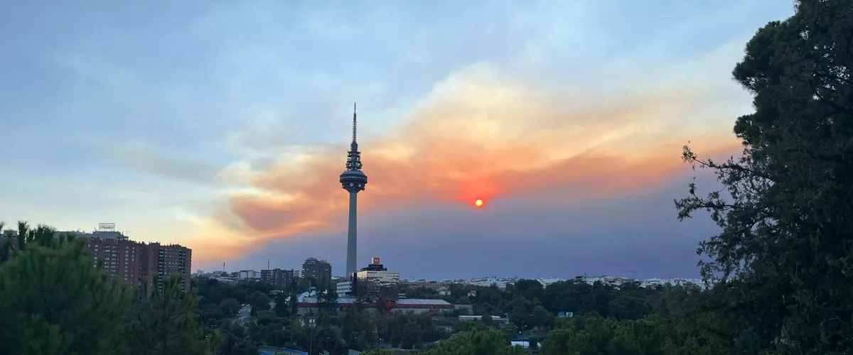 MADRID, 24/07/2026.- Vista del atardecer desde el pinar del barrio madrileño de La Elipa, influenciado por el humo del incendio que afecta al suroeste de la Comunidad de Madrid que mantiene en máxima alerta a los servicios de emergencia y ha obligado a ampliar las evacuaciones y confinamientos en varios municipios, mientras continua un amplio operativo para frenar el avance de las llamas. EFE/Francisco Camino
