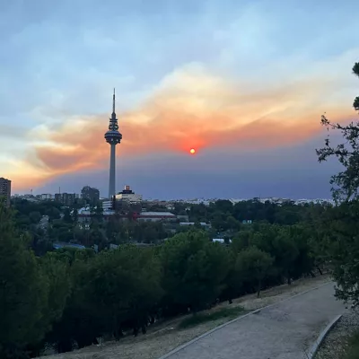 MADRID, 24/07/2026.- Vista del atardecer desde el pinar del barrio madrileño de La Elipa, influenciado por el humo del incendio que afecta al suroeste de la Comunidad de Madrid que mantiene en máxima alerta a los servicios de emergencia y ha obligado a ampliar las evacuaciones y confinamientos en varios municipios, mientras continua un amplio operativo para frenar el avance de las llamas. EFE/Francisco Camino

