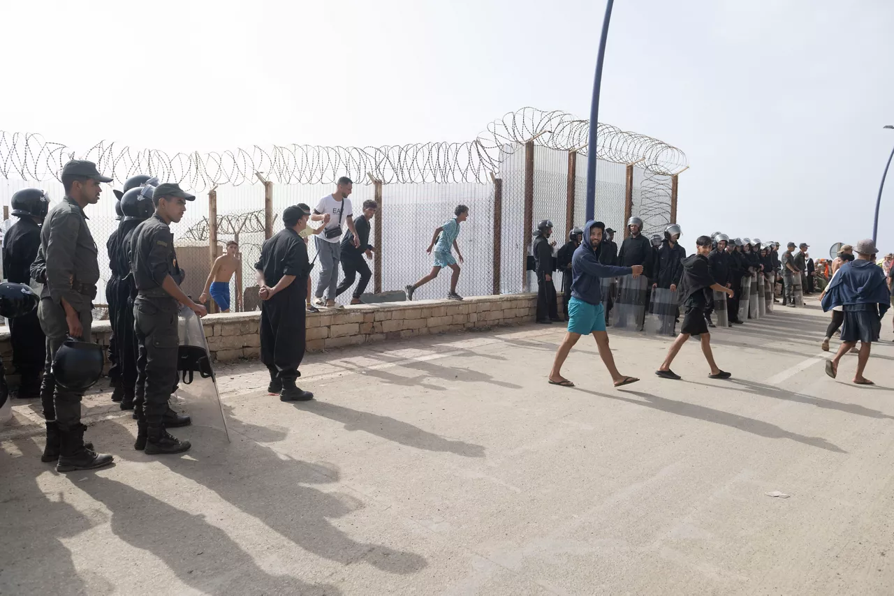 FNIDEQ (Morocco), 01/08/2026.- A group of undocumented migrants who returned from the Spanish enclave of Ceuta gather at the Bab Sebta border crossing near Fnideq, Morocco, 01 August 2026. The mass crossing prompted unrest and clashes near the border as Moroccan security forces sought to prevent further attempts to enter Ceuta. (Marruecos) EFE/EPA/JALAL MORCHIDI
