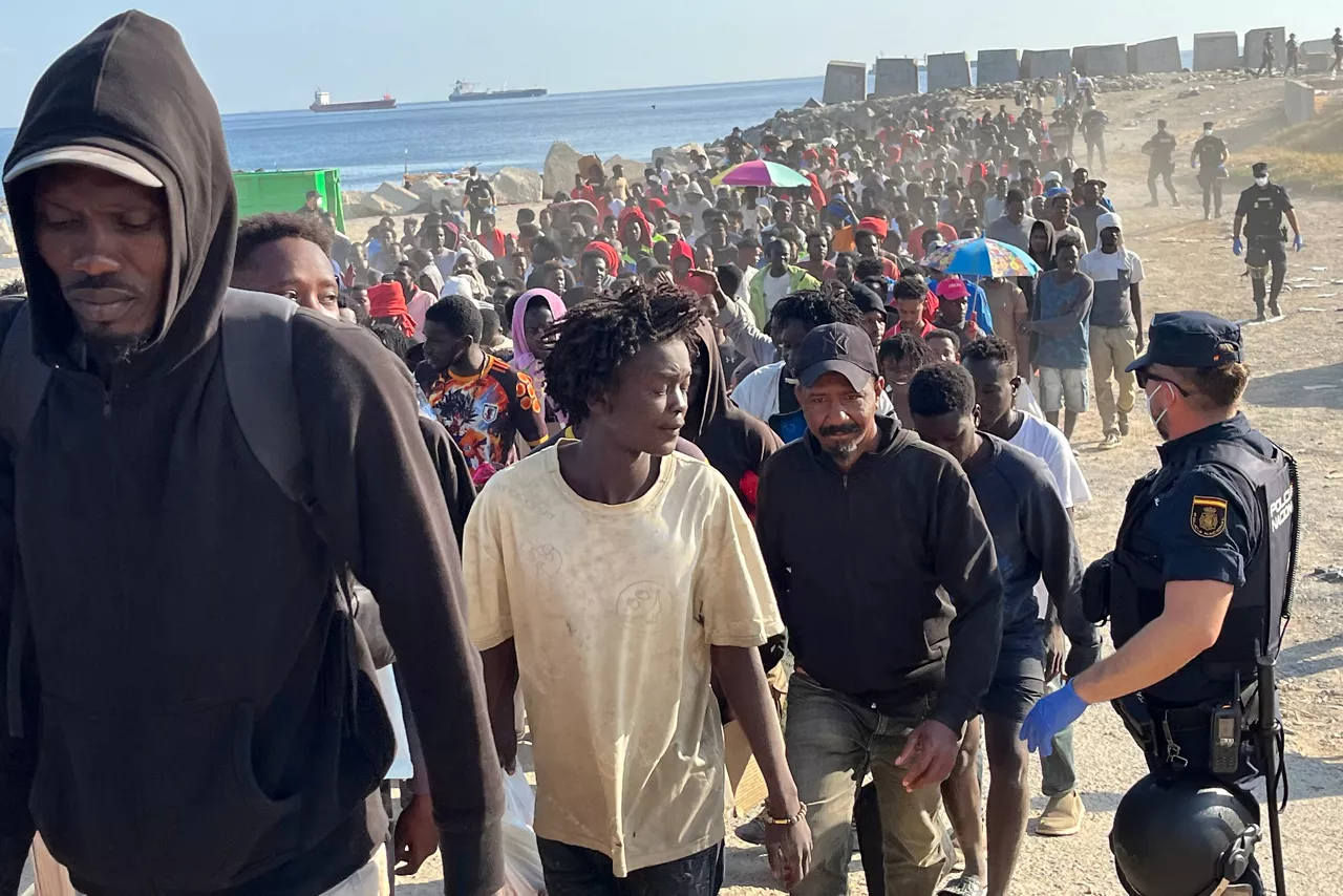 CEUTA, 20/08/2026.- Migrantes son desalojados de la playa del Trampolín en Ceuta tras habilitarse un espacio para su acogida este jueves. El Gobierno ha habilitado temporalmente varios espacios para la acogida de 1.800 personas migrantes que se encuentran en situación de calle en la playa del Trampolín y en la zona de Loma Colmenar, en Ceuta, que prevé ampliar progresivamente. EFE/Reduan
