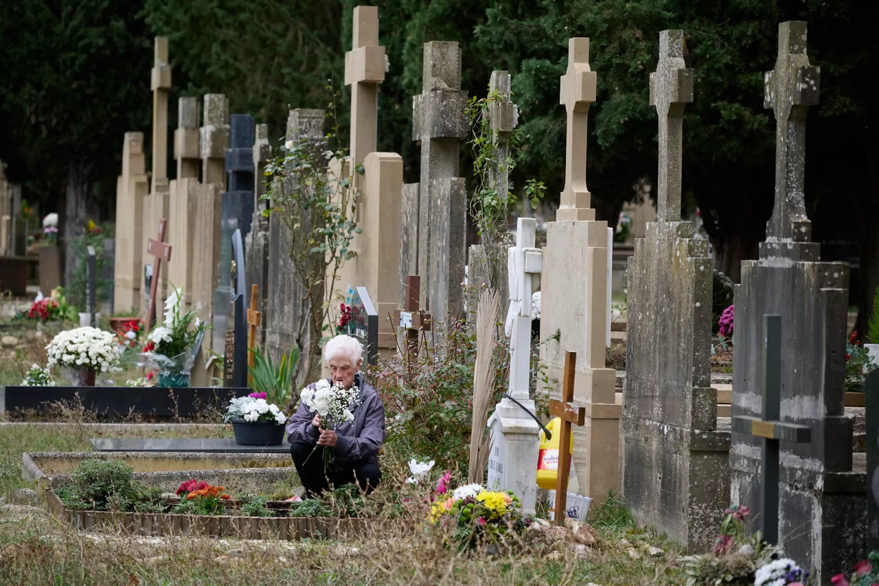 A woman visits the tomb of a beloved one at the cemetery of the town of Pamplona during All Saints Day, in Navarra, northern Spain, 01 November 2025. Spaniards visit cemeteries to remember their late relatives bringing them flowers and cleaning their tombs. EFE/ Inaki Porto
