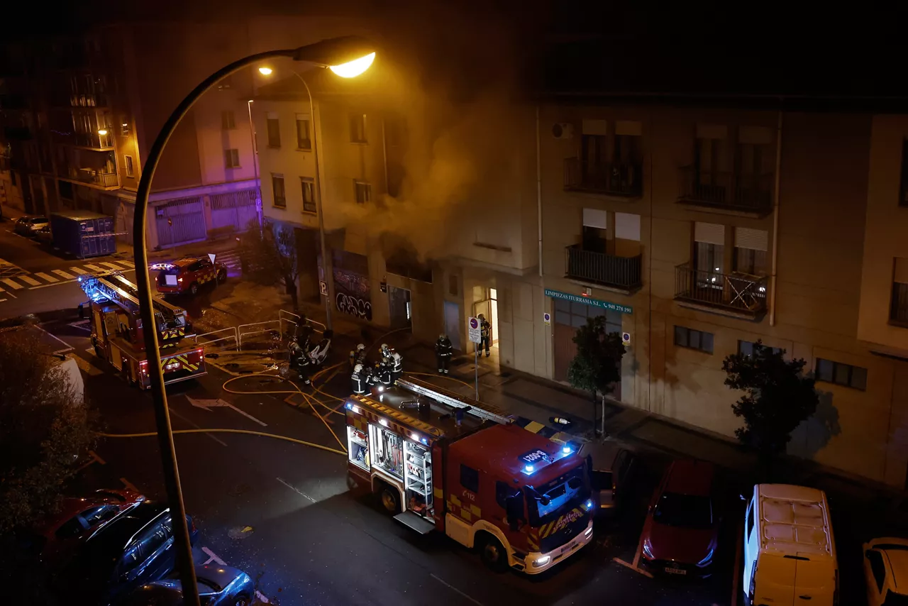 GRAFCAV7054. PAMPLONA, 26/11/2025.- Los Bomberos de Navarra trabajan en la extinción de un incendio en un bazar de la calle Marcelo Celayeta del barrio pamplonés de la Rochapea, que mantiene confinados a los vecinos por la toxicidad del humo y ha obligado a desalojar tres edificios. Dos personas han sido atendidas por una intoxicación leve en el lugar por una ambulancia de soporte vital básico sin que en ningún caso haya sido necesario el traslado a un centro sanitario. El incendio ha comenzado a las 17:31 horas a la altura del portal 100 de la citada calle. Hasta el lugar han acudido Bomberos de Trinitarios y de Cordovilla, dos ambulancias y la Policía Municipal de Pamplona.EFE/ Jesús Diges
