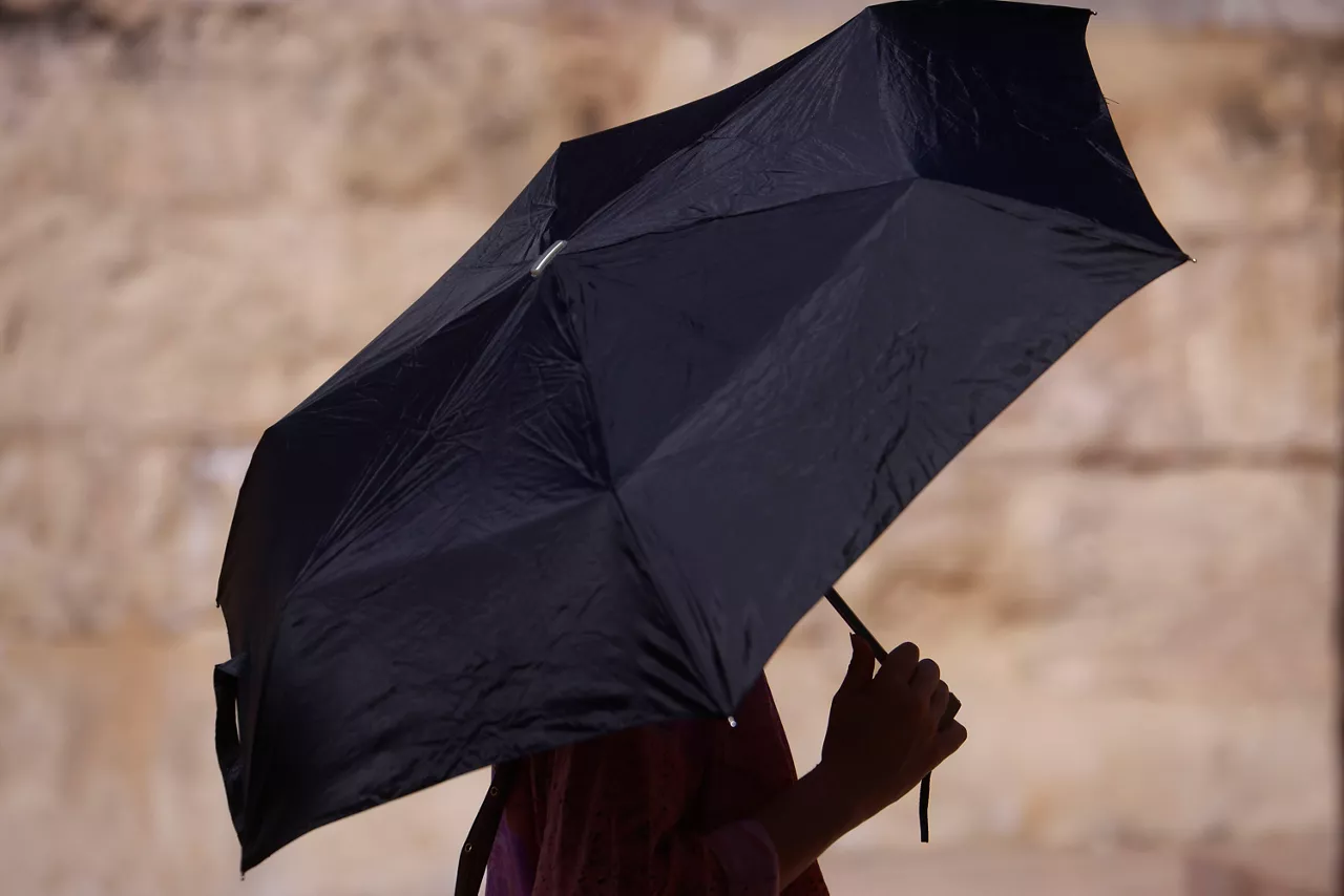 CÓRDOBA, 20/06/2026.- Una persona se protege con un paraguas ante las altas temperaturas de este sábado en Córdoba. Siete Comunidades -Andalucía, Aragón, Baleares, Cantabria, Castilla y León, Cataluña y País Vasco- están hoy en aviso naranja (peligro importante) por temperaturas de hasta 40 grados, lluvias y tormentas y otras siete en amarillo (riesgo para ciertas actividades). EFE/ Salas
