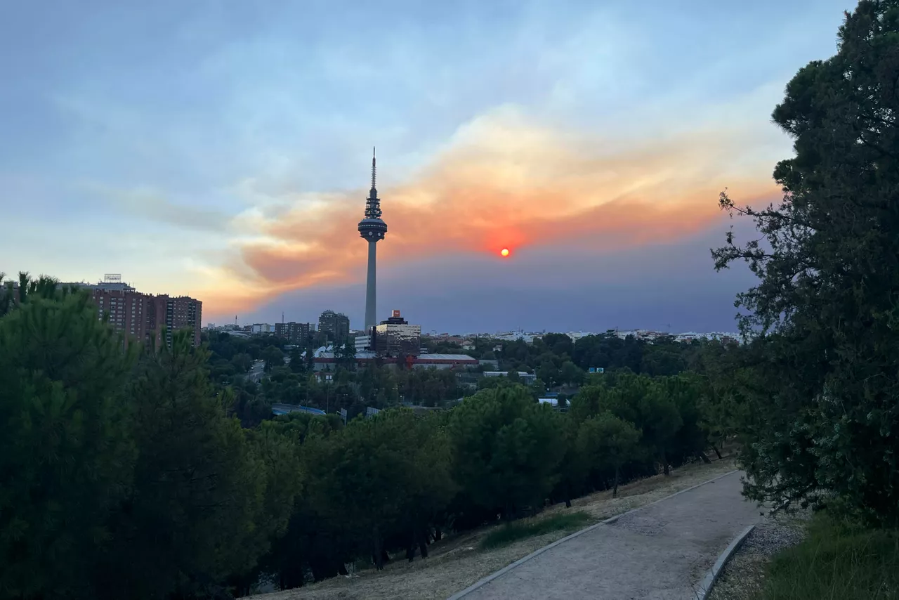 MADRID, 24/07/2026.- Vista del atardecer desde el pinar del barrio madrileño de La Elipa, influenciado por el humo del incendio que afecta al suroeste de la Comunidad de Madrid que mantiene en máxima alerta a los servicios de emergencia y ha obligado a ampliar las evacuaciones y confinamientos en varios municipios, mientras continua un amplio operativo para frenar el avance de las llamas. EFE/Francisco Camino
