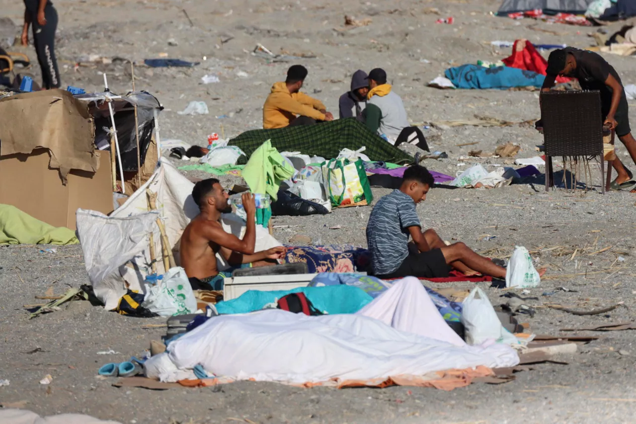 CEUTA, 22/08/2026.- Varios migrantes permanecen acampados este sábado en la playa El Trampolín de Ceuta. Varios migrantes regresaron a pesar de que agentes españoles volvieron a desalojar ayer a los más de mil migrantes que se encontraban en la playa. EFE/ Reduan
