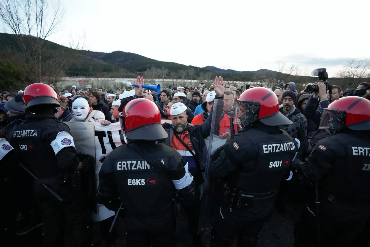 MURRIO (ÁLAVA), 09/02/2026.- Trabajadores tras un cordón de la Ertzaintza durante una manifestación convocada en el acceso a la fábrica de Tubos Reunidos en la localidad alavesa de Murrio, este lunes, tras el inicio anoche de una huelga convocada a la espera de conocer el número de afectados por el ERE. EFE/ Adrián Ruiz Hierro
