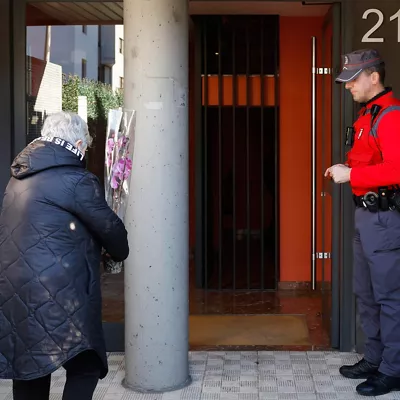 SARRIGUREN, 21/02/2026.- Una mujer deja una planta en el portal de la vivienda de Sarriguren donde dos mujeres fueron víctimas, una de ellas asesinada presuntamente por su marido, en un caso de violencia machista y la otra herida de gravedad. El Ayuntamiento del Valle de Egüés ha decretado tres días de luto oficial. EFE/ Jesús Diges
