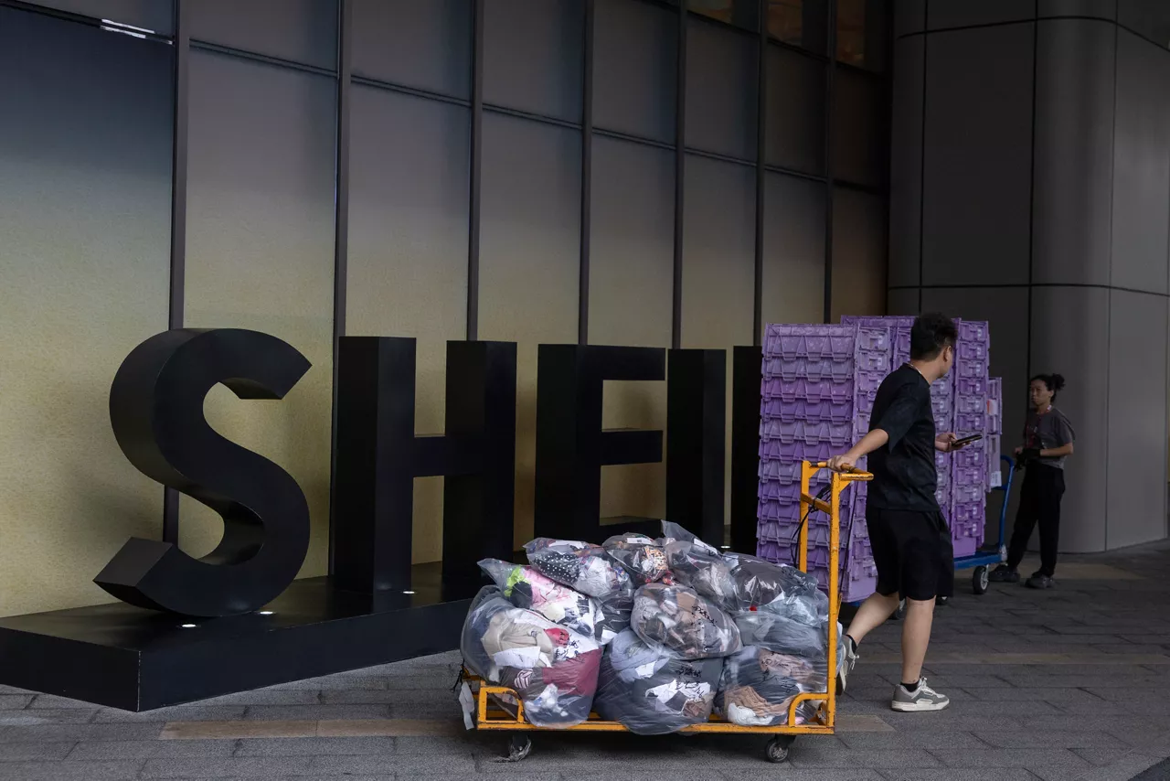 GUANGZHOU (China), 26/08/2026.- A man pulls a cart past the logo of SHEIN as seen outside of a building in Guangzhou, in the province of Guangdong, China, 26 August 2026. Shein Global Holdings Ltd. is scheduled to begin trading on the Hong Kong Stock Exchange on 01 September 2026. EFE/EPA/ANDRES MARTINEZ CASARES
