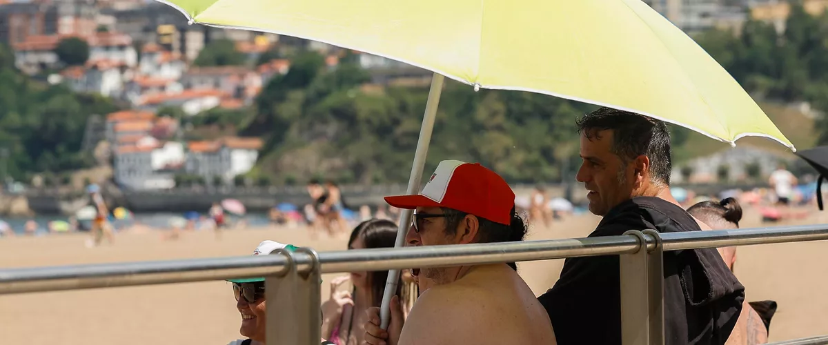 GETXO (BIZKAIA), 21/06/2026.- Varias personas se resguardan del sol en la playa de Ereaga en Getxo (Bizkaia) este domingo, jornada en la que el Departamento vasco de Seguridad ha elevado la alerta a roja por la ola de calor al esperarse temperaturas muy altas que alcancen los 40 grados.  EFE/ Miguel Toña
