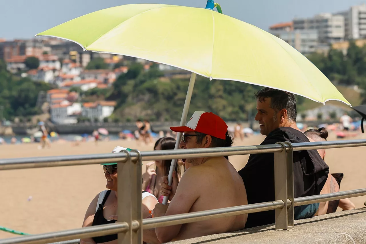 GETXO (BIZKAIA), 21/06/2026.- Varias personas se resguardan del sol en la playa de Ereaga en Getxo (Bizkaia) este domingo, jornada en la que el Departamento vasco de Seguridad ha elevado la alerta a roja por la ola de calor al esperarse temperaturas muy altas que alcancen los 40 grados.  EFE/ Miguel Toña
