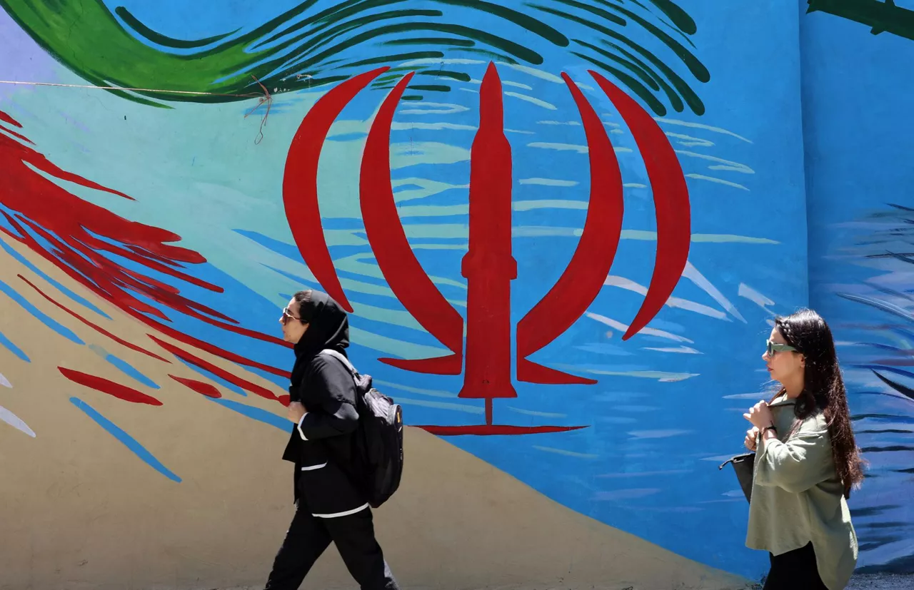 FOTODELDÍA TEHERÁN (Irán), 15/06/2026.- Ciudadanos iraníes pasan junto a un mural con la bandera nacional de Irán en una calle de Teherán, Irán, este lunes. El presidente estadounidense Donald Trump anunció en sus redes sociales que se ha alcanzado un acuerdo con Irán, el cual se firmará el 19 de junio en Suiza. (Suiza, Teherán) EFE/EPA/ABEDIN TAHERKENAREH RESTRICCIONES: Prohibido el acceso a medios de comunicación israelíes/canales de televisión en persa fuera de Irán/Prohibido el acceso a BBC Persian/VOA Persian/Manoto TV/Televisión Internacional de Irán. (Según lo dispuesto por la Dirección General de Medios de Comunicación Extranjeros de Irán)
